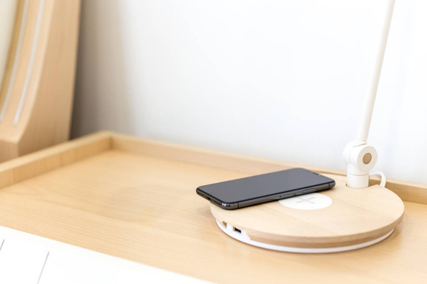 Carregamento de smartphone sem fio na lâmpada perto da cama
 - Foto, Imagem