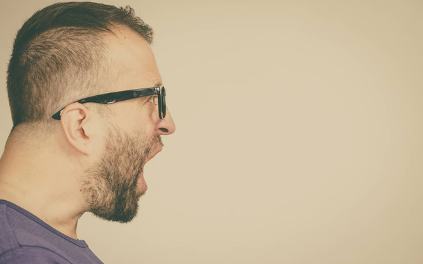 Adult man wearing eyeglasses yelling at somebody. Side profile view with copy space - Foto, Imagem