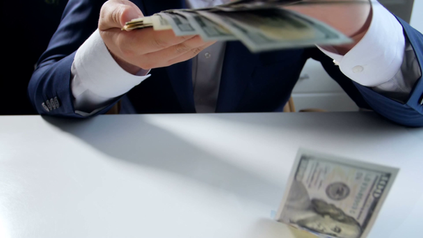 Повільні кадри руху заможного бізнесмена кидають гроші з великої стопки на камеру
 - Кадри, відео