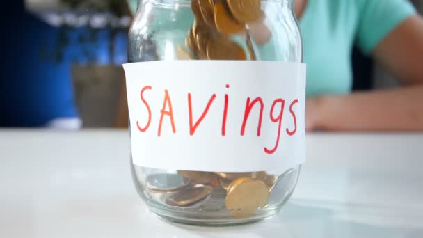 Imagens de movimento Slkow de uma jovem mulher enchendo jarro de vidro para economizar dinheiro
 - Filmagem, Vídeo