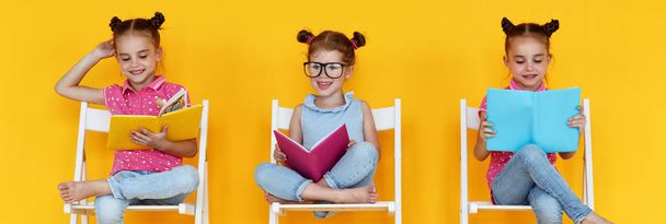 funny children girls read books on a colored yellow backgroun - Foto, imagen
