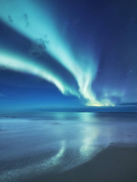 Aurora boreal en las islas Lofoten, Noruega. Luces verdes del norte sobre el océano. Cielo nocturno con luces polares. Paisaje nocturno de invierno con aurora y reflexión sobre la superficie del agua. Contexto natural en Noruega
 - Foto, Imagen