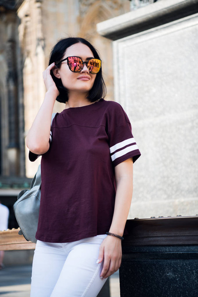 Молода стильна дівчина, одягнена в модні окуляри та футболку. Абстрактний погляд на бік. концепція вуличної моди
. - Фото, зображення