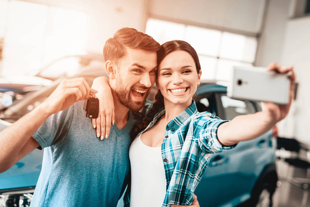 A Man And A Woman Do Selfie Near Their New Car. Automobile Salon. Make A Decision. Happy Together. Great Offer. Happy Together. Successful Buying. Good Mood. Business Trade. - Fotoğraf, Görsel