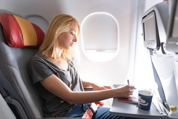 Випадкова жінка літає на літаку комерційних пасажирів, заповнюючи форму імміграції
. - Фото, зображення