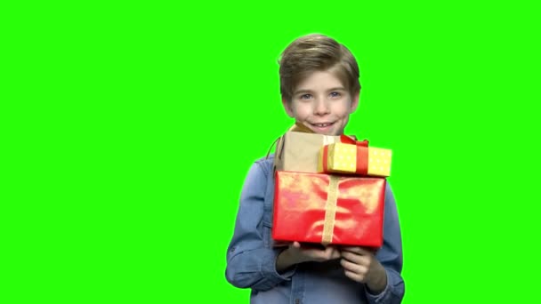 Portret van de kleine jongen in denim jasje met geschenkdozen. - Video