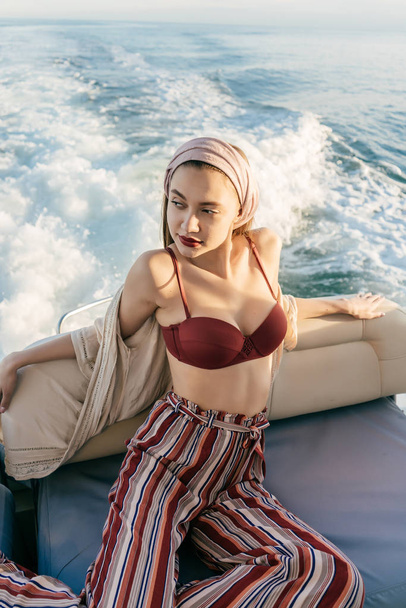 slim sexy girl in a swimsuit and with a headscarf on her head posing and resting on her yacht, sailing the Caribbean sea - Photo, image