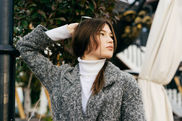 beautiful young brunette girl in gray coat posing outdoors, street style and fashion - 写真・画像