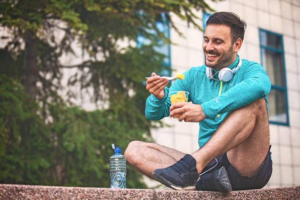Young athlete man eating fruit after exercising.  - Valokuva, kuva