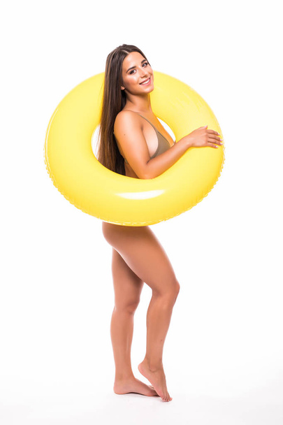 Portrait of an young woman dressed in swimsuit posing with inflatable ring isolated over white background - Foto, Bild