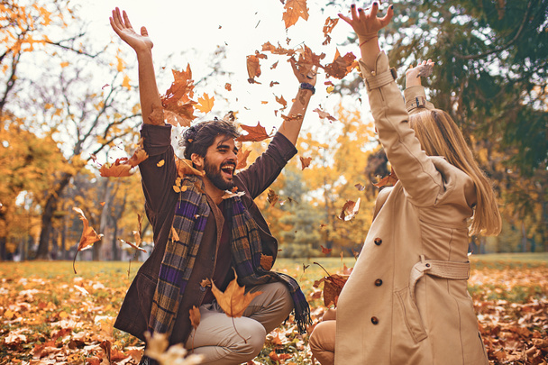 Young smiling couple enjoying fall in the park. - Фото, зображення