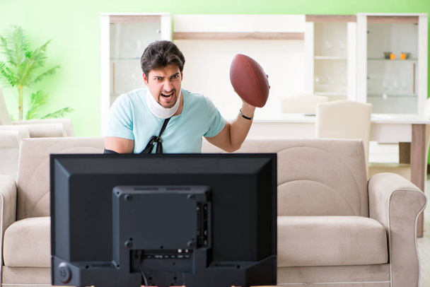 Man with neck and arm injury watching american football on tv - Photo, Image