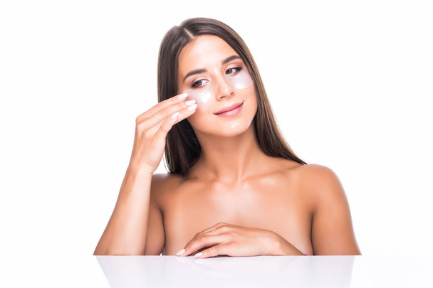 Close up portrait of pretty, charming, attractive girl with naked shoulders using, having, applying patches under close eyes, fight with dark circles, standing over white background, wellbeing concept - Fotó, kép