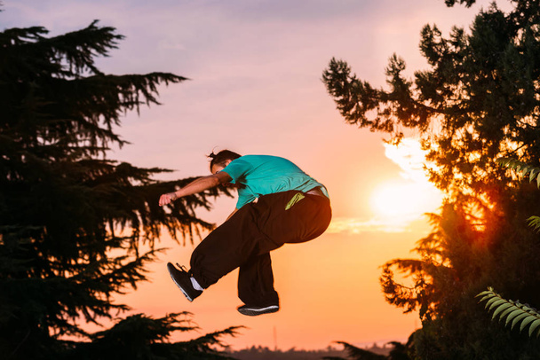 Вільний бігун робить паркур вправи на відкритому повітрі під час заходу сонця
 - Фото, зображення
