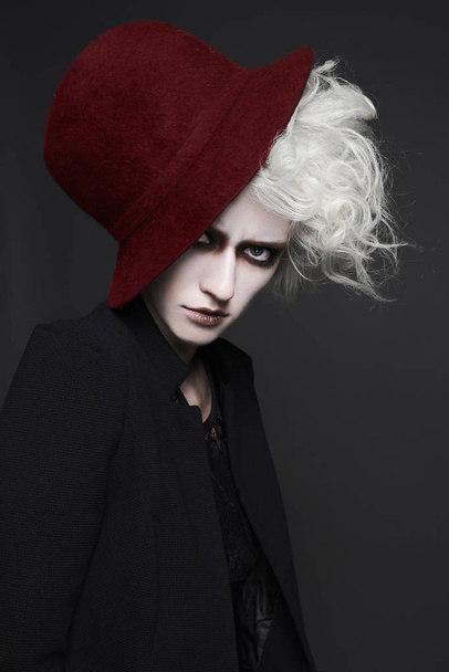 fashion close-up portrait of halloween make-up woman in red hat.white skin and hair fairy girl - 写真・画像