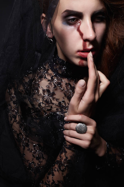 sad woman in black veil with a bloody face make-up.halloween costume.black widow - Foto, Imagen