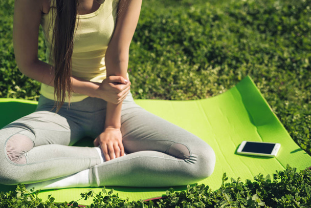 slender young girl meditates, sits on a rug for yoga in the park, leads a healthy lifestyle - Foto, Imagen
