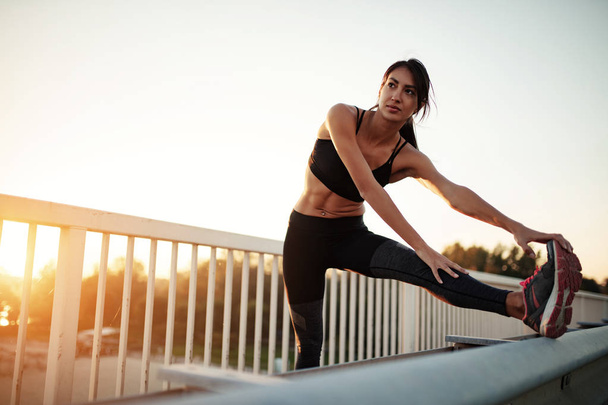 Athlete woman stretching her legs outdoors. - 写真・画像