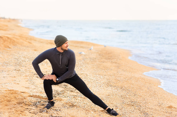 man doing stretch exercises on the sea beach - Foto, Imagen