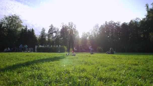 Young attractive girl riding a gyro on the grass. Summer day. The glare of the sun. - Materiał filmowy, wideo