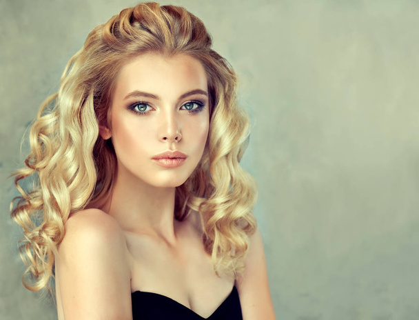 blond girl with long and shiny curly hair . Beautiful model woman with curly hairstyle .Care and beauty - Photo, Image