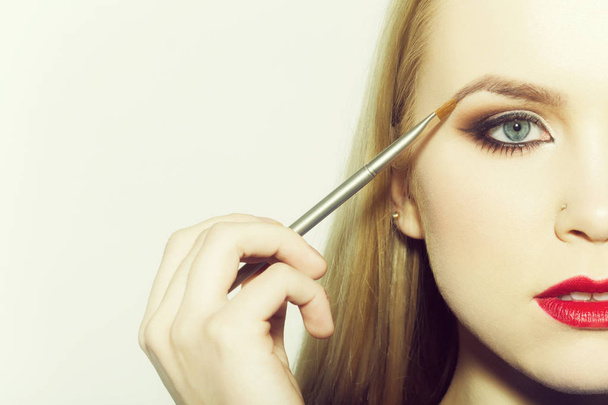 Woman applying eyeshadow on eye with makeup brush - Фото, изображение