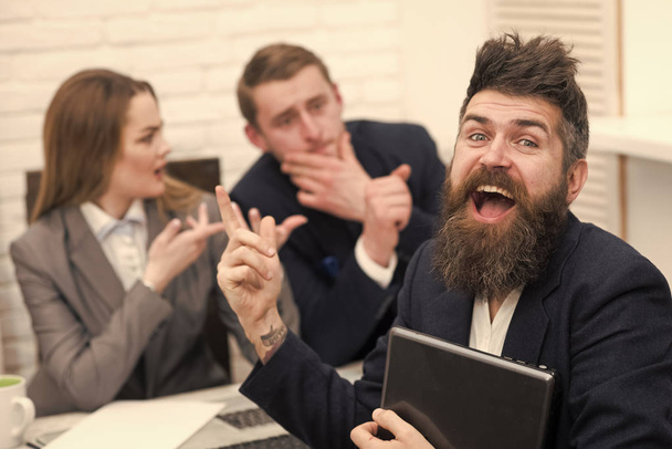 Man with beard on happy face holds laptop, bosses, coworkers, colleagues on background. Successful job interview concept. Man got job, successful meeting. Man surprised, hired for work in office. - Photo, Image