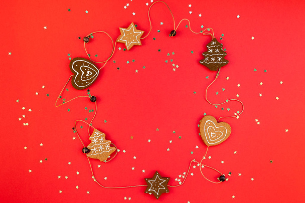 Новорічна або різдвяна прикраса квартири вигляд зверху Різдвяні свята святкування ручної роботи цукерки золоті зірки блиск на червоному папері фоні. Шаблон рамки для вітальної листівки вашого дизайну
 - Фото, зображення