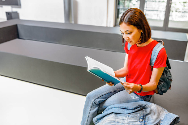 κορίτσι φοιτητής διαβάζοντας ένα βιβλίο σε ένα εσωτερικό σύγχρονη βιβλιοθήκη στο Πανεπιστήμιο - Φωτογραφία, εικόνα