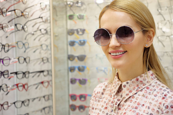 young woman is choosing a solar glasses in optician store. - Foto, Imagem