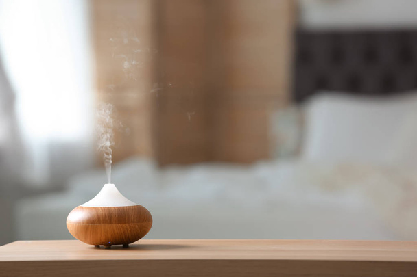 Aroma oil diffuser lamp on table against blurred background - Valokuva, kuva