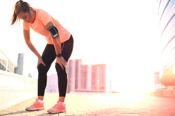 Fiatal fitness vonzó sportos lány pihenés után intenzív esti futás szabadban naplementekor a városban. - Fotó, kép