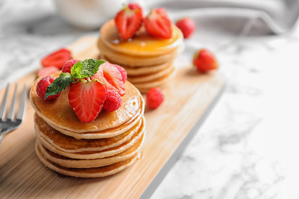 Tasty pancakes with berries on wooden board - 写真・画像