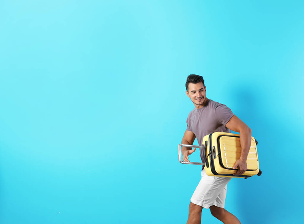 Young man with suitcase on color background. Space for text - Foto, imagen