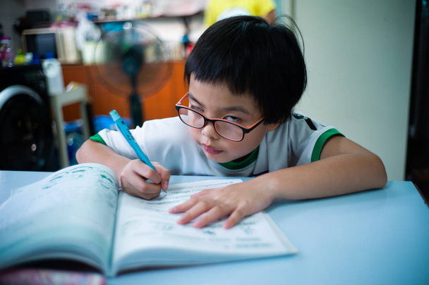 Ritratto di bambina asiatica che fa i compiti dopo la scuola a casa con il viso divertente
. - Foto, immagini