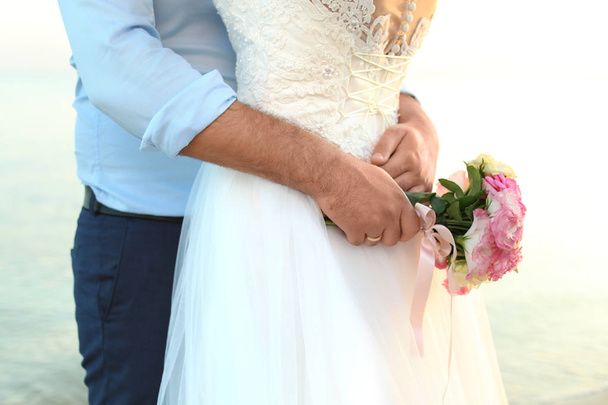 Wedding couple with beautiful bouquet on beach - Фото, зображення