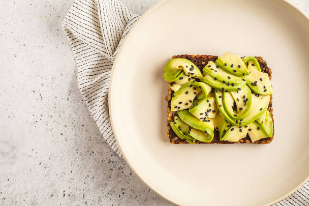 Avocado toast on a healthy sesame bread with sesame seeds on white background, copy space. Healthy vegan food concept. - Foto, afbeelding