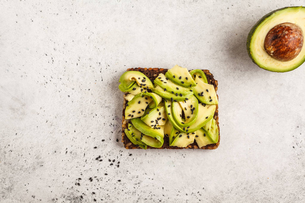 Avocado toast on a healthy sesame bread with sesame seeds on white background, copy space. Healthy vegan food concept. - Foto, Imagen