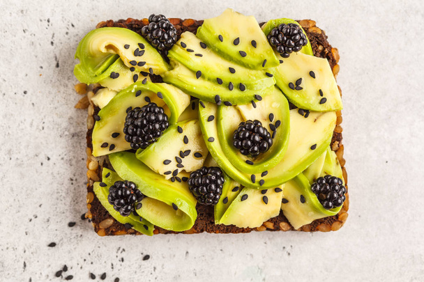 Avocado toast on a healthy sesame bread with sesame seeds on white background. Healthy vegan food concept. - Foto, afbeelding