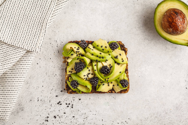 Avocado toast on a healthy sesame bread with sesame seeds on white background, copy space. Healthy vegan food concept. - Foto, afbeelding