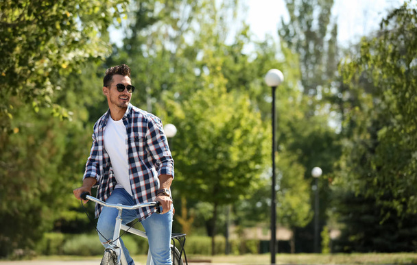 Handsome young hipster man with bicycle near wooden wall outdoors - Foto, Imagen
