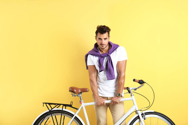Handsome young hipster man with bicycle on yellow background - Foto, immagini