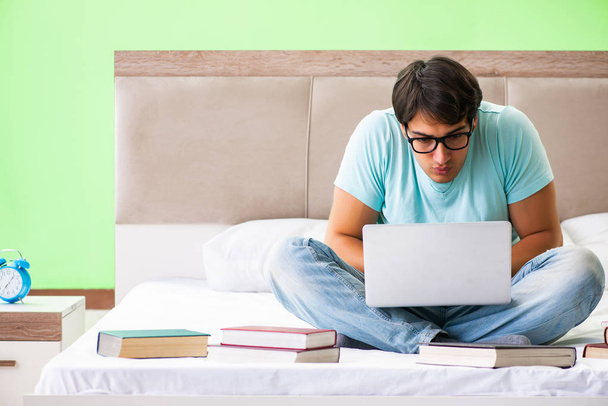 Student preparing for exams at home in bedroom sitting on the be - Photo, Image