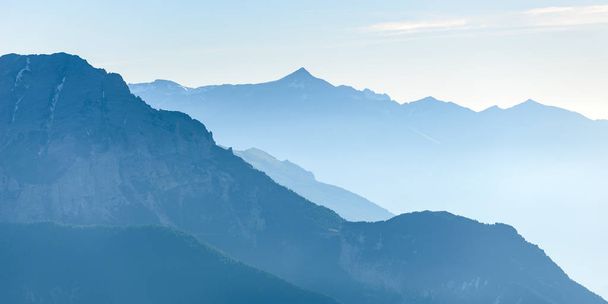 Kaukainen sininen vuorijono majesteettisen Euroopan Alpeilla sumu ja sumu laaksossa alla
 - Valokuva, kuva