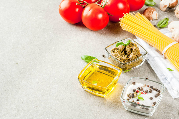 Food background, ingredients for cooking dinner.  Pasta spaghetti, vegetables, sauces and spices, grey stone background copy space  - Photo, Image