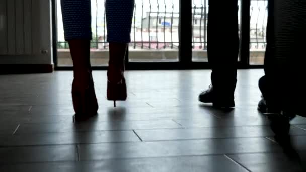 Silhouet van man en vrouw voeten lopen naar de grote ramen van office - Video