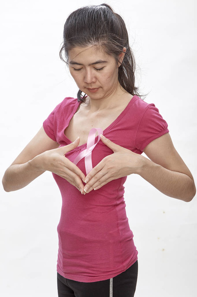 女性の胸にピンクがんリボンを wih。医療、医学、乳房癌意識の概念。スタジオ撮影、明るい白背景、健康保険 - 写真・画像