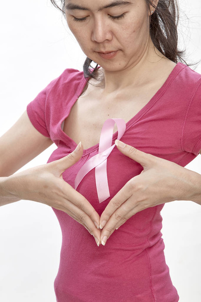 Vrouw roze kanker lint op borst. Gezondheidszorg, geneeskunde en borst kanker bewustzijn concept. Studio schoot, lichte witte achtergrond, Insurance Health System - Foto, afbeelding