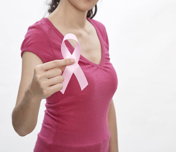 女性の胸にピンクのがんリボン。医療、医学、乳房癌意識の概念。スタジオ撮影、明るい白背景、健康保険 - 写真・画像