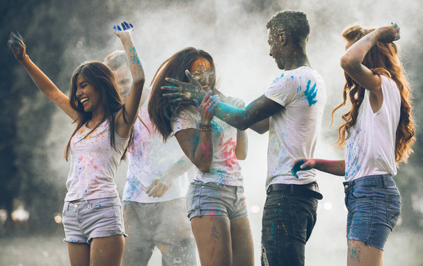 Group of teens playing with colors at the holi festival, in a park - Фото, зображення